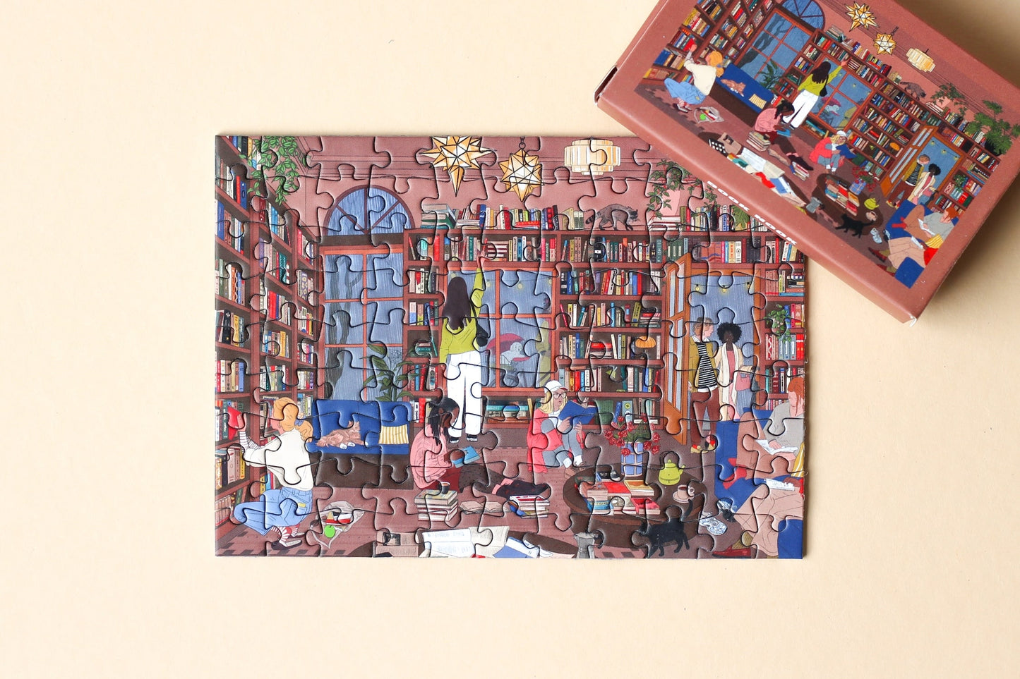 99-Teile-Mini-Puzzle „Book Nook“ von Piecely – Illustration eines gemütlichen Leseraums mit Bücherregalen und Menschen beim Lesen, auf brauner Verpackung.