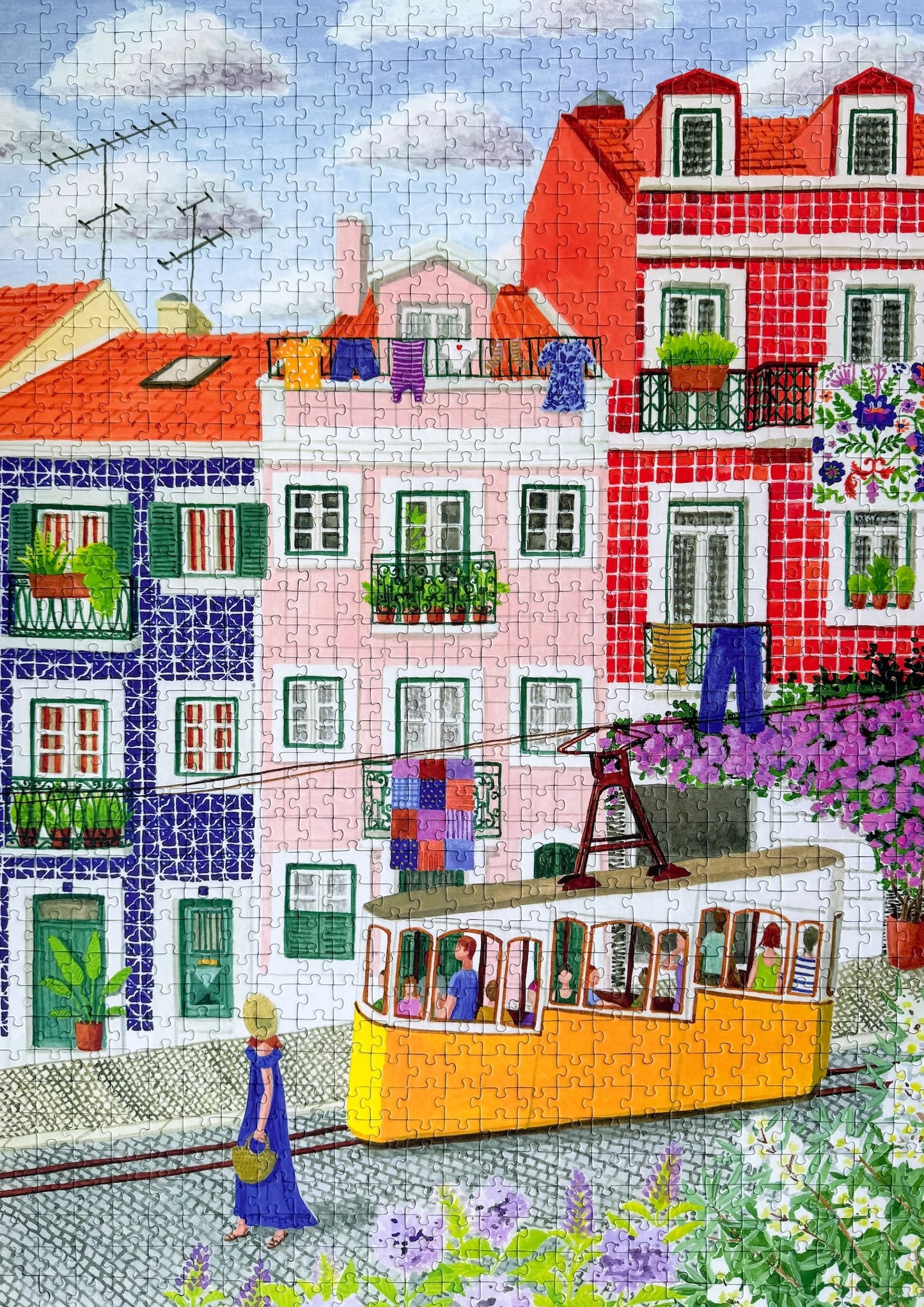 1000-Teile-Puzzle „Lisbon“ von Piecely – Illustration einer farbenfrohen Straßenszene in Lissabon mit gelber Straßenbahn und bunten Häusern, auf pinker Verpackung.