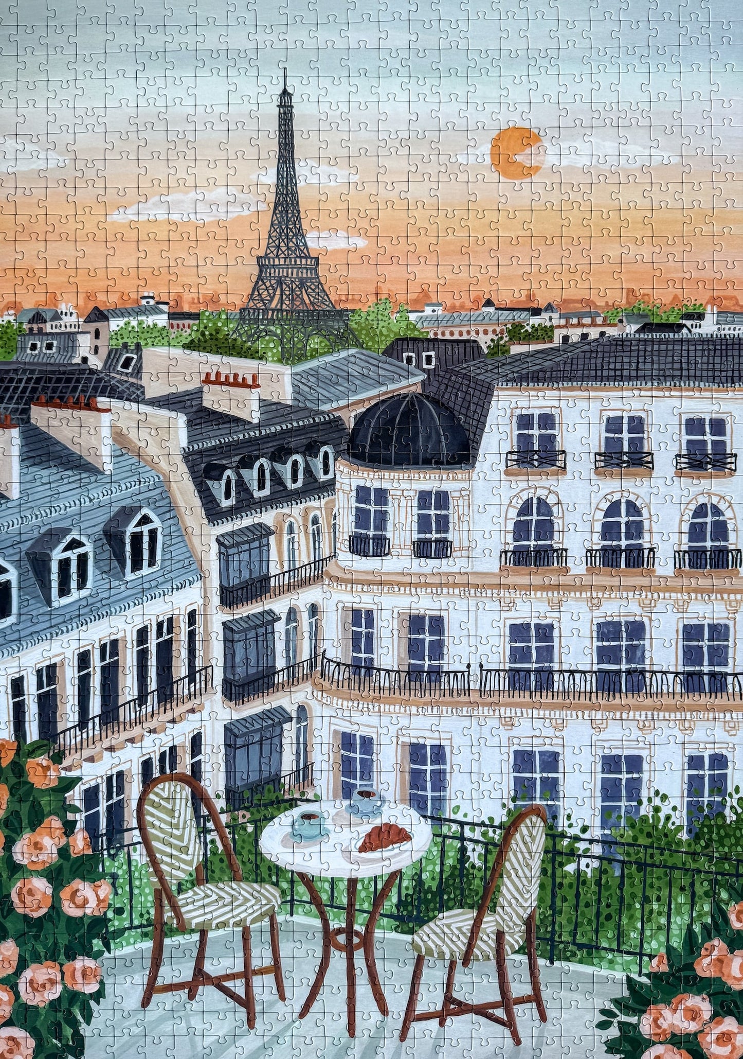 1000-Teile-Puzzle „Paris“ von Piecely – Illustration eines Pariser Balkons mit Frühstückstisch und Blick auf den Eiffelturm, auf hellblauer Verpackung.
