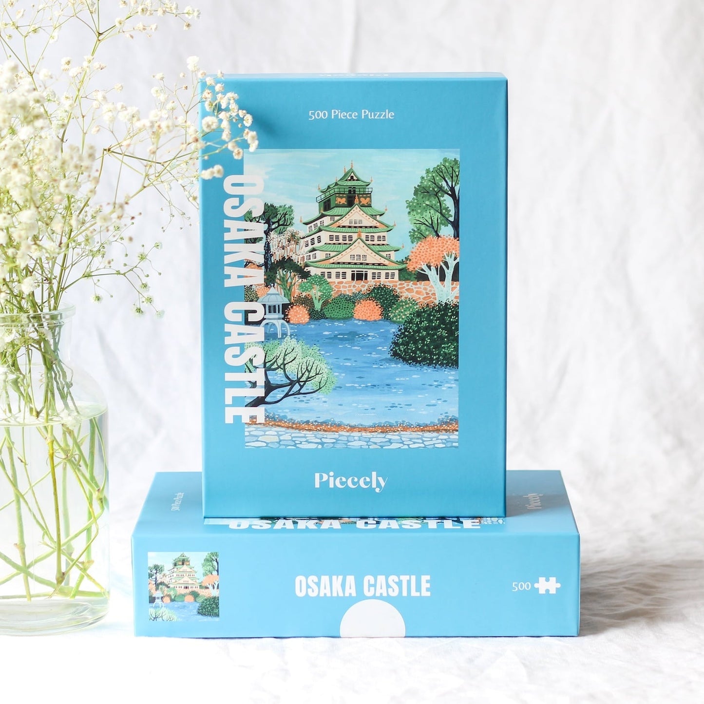 Plastikfreies Puzzle für Erwachsene, das die Burg Osaka in Japan in pastelligen Blau- und Grüntönen zeigt.