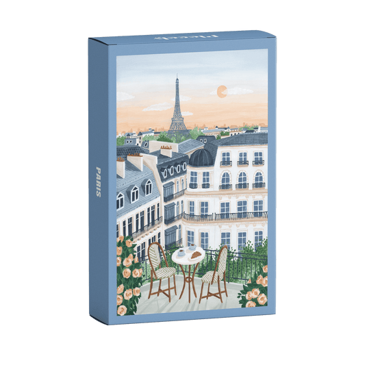 99-Teile-Mini-Puzzle „Paris“ von Piecely – Illustration eines Pariser Balkons mit Frühstückstisch, Rosen und Blick auf den Eiffelturm, auf hellblauer Verpackung.