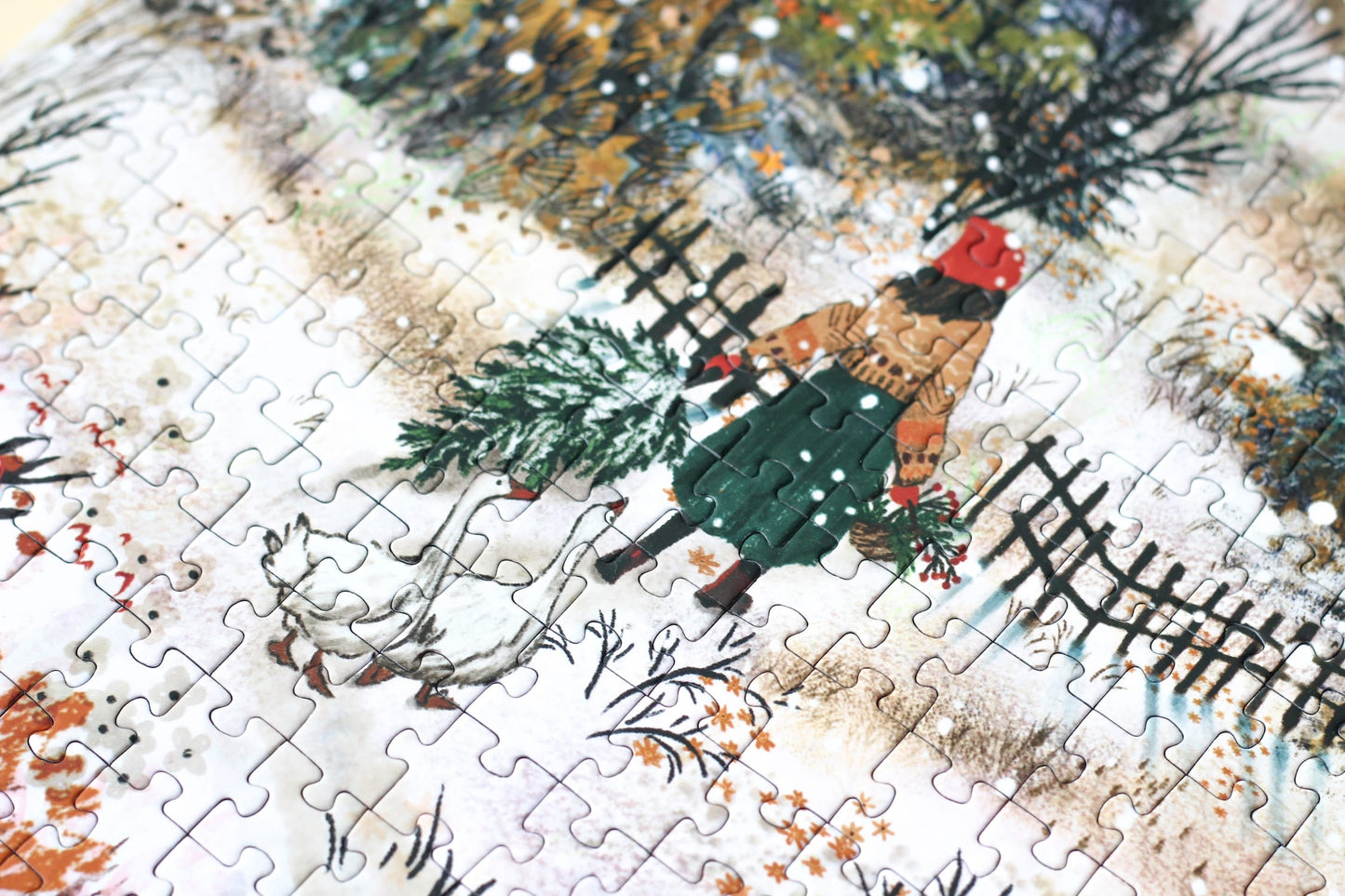 500-Teile-Puzzle „Homecoming“ von Piecely – Illustration einer winterlichen Landschaft mit Frau und zwei Gänsen auf einem verschneiten Weg, auf grauer Verpackung.