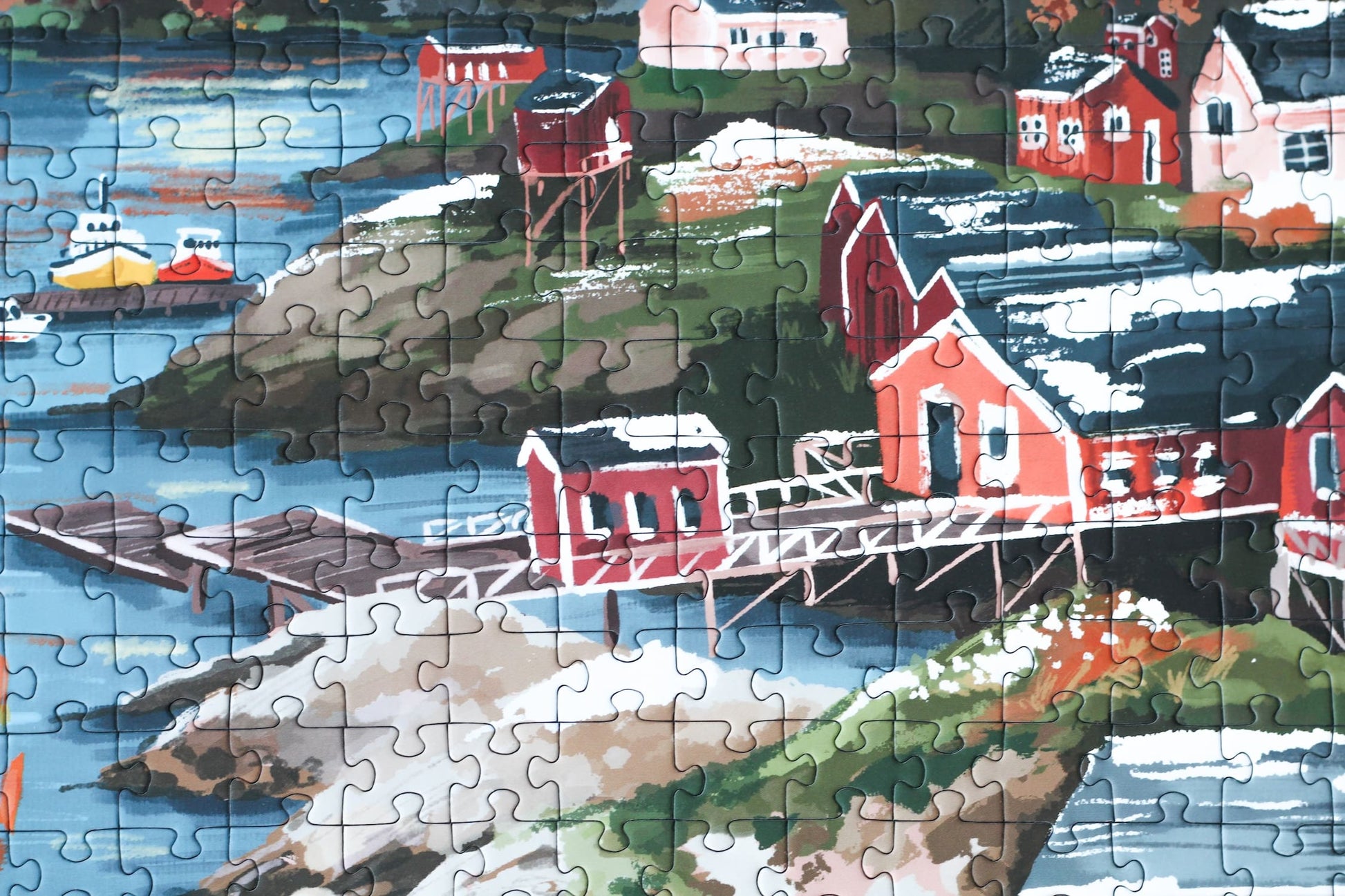 1000-Teile-Puzzle „Lofoten Norway“ von Piecely – Illustration einer norwegischen Küstenlandschaft mit schneebedeckten Bergen, roten Holzhäusern und Meer, auf olivgrüner Verpackung.