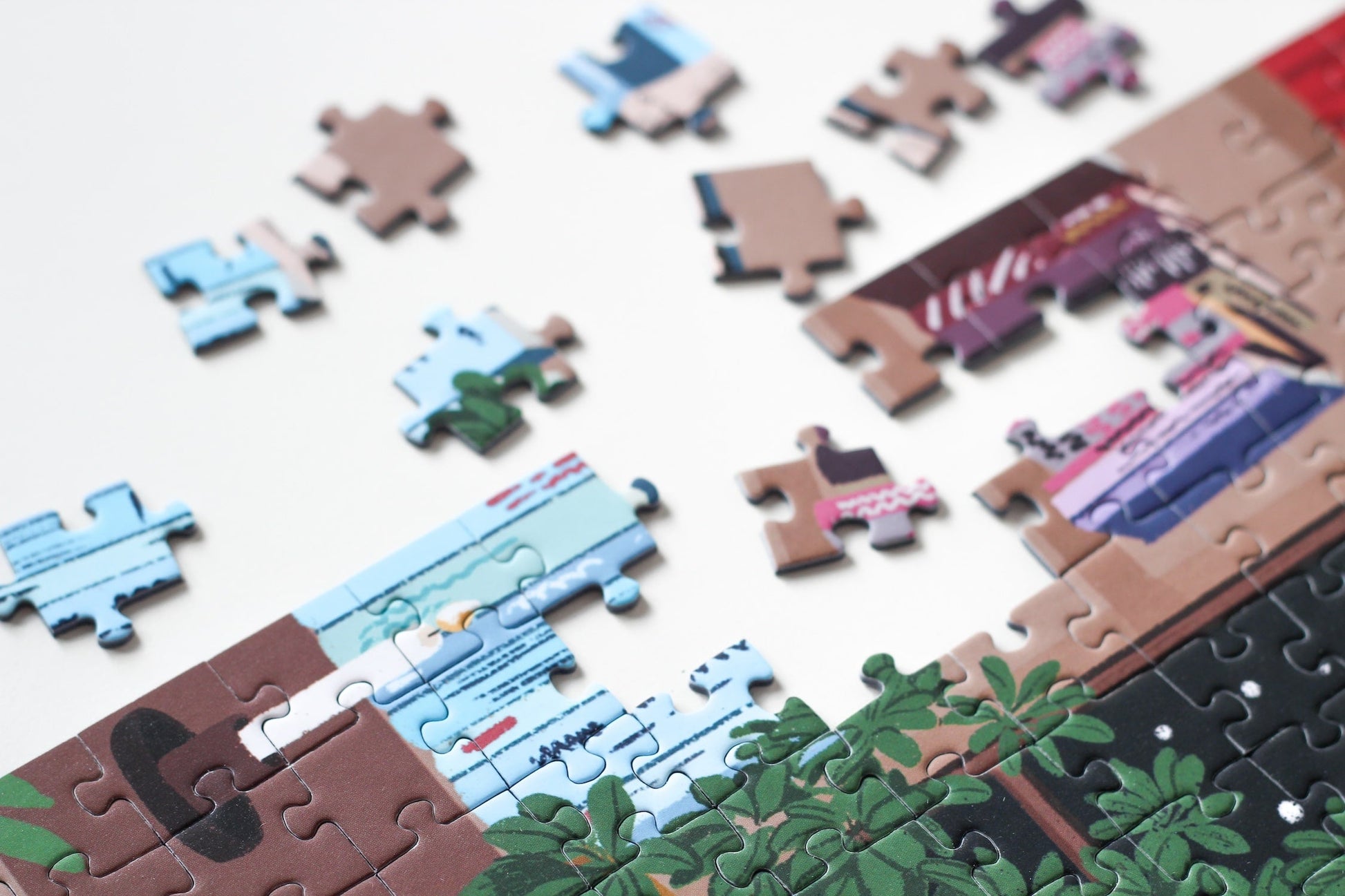 Nachhaltiges 1000-Teile-Puzzle, das eine Frau mit einem Stapel Bücher in der Hand zeigt. Im Hintergrund ist ein prall gefülltes Bücherregal und zwei süße Katzen.