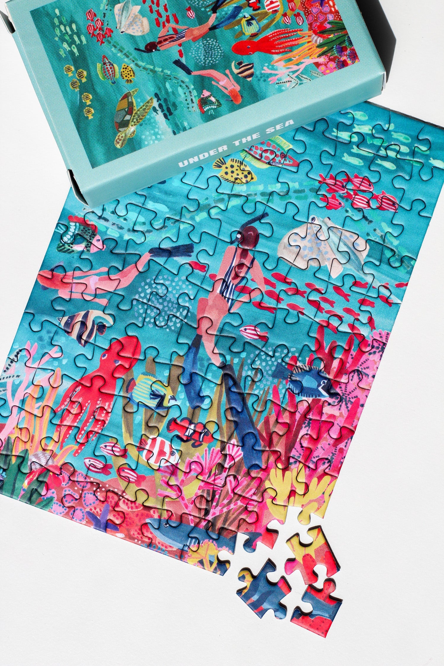 99-teiliges Under The Sea Minipuzzle für Erwachsene, das zwei Frauen beim Schnorcheln im Meer zeigt. Die Frauen sind umgeben von bunten Fischen, einem Oktopus, einem Rochen, einer Schildkröte und einem Hai. 