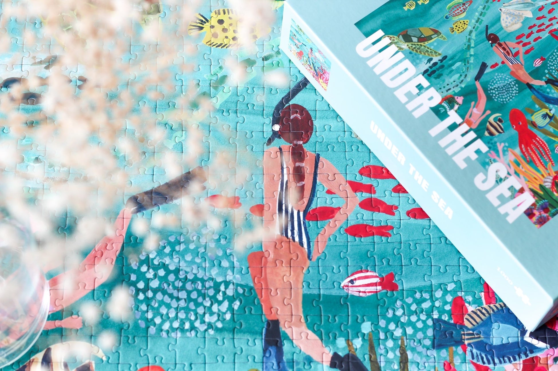 10000-teiliges, nachhaltiges Puzzle für Erwachsene, das eine farbenfrohe Unterwasserlandschaft mit Taucherinnen, Fischen, einem Hai, einer Schildkröte, einem Oktopus und einem Rochen zeigt.