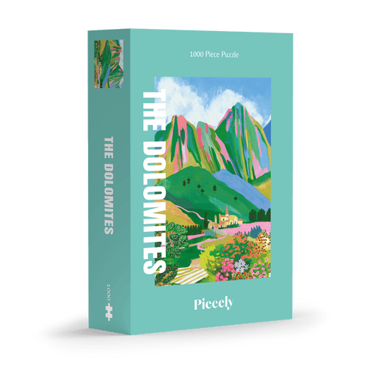 1000-Teile-Puzzle „The Dolomites“ von Piecely – Illustration einer farbenfrohen Berglandschaft in den Dolomiten mit Dorf und Blumen, auf türkisfarbener Verpackung.
